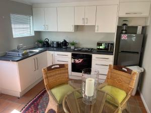 赫曼努斯Joy@Grotto Beach, Hermanus的厨房配有桌椅和冰箱。