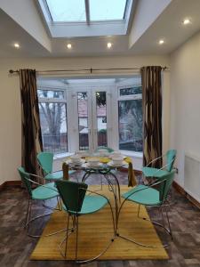 海丁利Super 7Bed House - Hot Tub - Large Gathering Meets的一间设有玻璃桌和绿色椅子的用餐室
