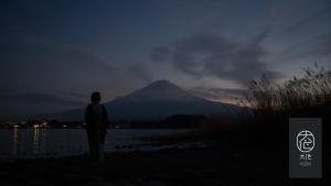 富士河口湖汤雾富士之宿 大池酒店的一个人在晚上站在山前