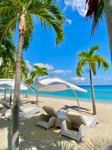 圣吉吉Seven Secrets by Hanging Gardens的海滩上设有白色的椅子和遮阳伞,还有大海