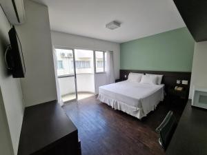 贝洛奥里藏特Hotel San Diego Pampulha - Flats Particular的卧室配有白色的床和电视。