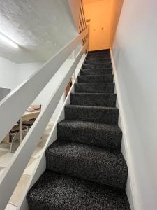 斯塔利桥Comfortable, spacious 2 Bedroom house close to Etihad Stadium的一座黑地毯房子里的楼梯