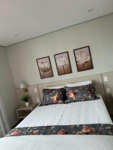 大坎普Flat próximo ao Shopping Campo Grande的卧室配有一张四幅画的墙壁床。