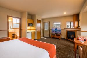 卡农海滩坎农比奇酒店的一间卧室配有一张床、一台电视和一个壁炉