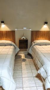 图努扬Hospedaje Los Ilustres的一间带两张床的卧室,铺有瓷砖地板。