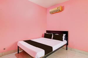 克塔克OYO MAA BHUASUNI RESIDENCY的粉红色墙壁的房间里一张床位