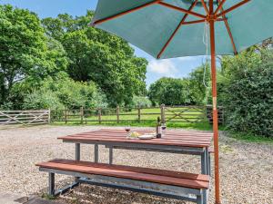 斯特明斯特牛顿3 bed property in Sturminster Newton Dorset RCORN的一张带绿伞和长凳的野餐桌
