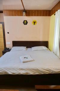 奈尼塔尔Sukoon Lake view BnB by Boho Stays的卧室配有白色的床和2条毛巾