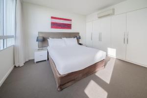 尼尔森湾Oaks Nelson Bay Lure Suites的白色的卧室设有一张大床和一个窗户