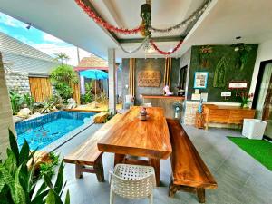 华欣华欣阿拉万泳池度假屋的一间带木桌和游泳池的用餐室