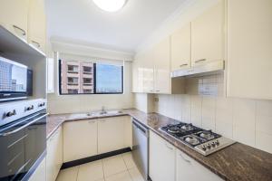 悉尼Oaks Sydney Castlereagh Suites的厨房配有白色橱柜和炉灶烤箱。