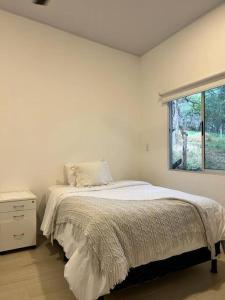 LagunillasJaco, Peace Home around nature的白色的卧室设有床和窗户