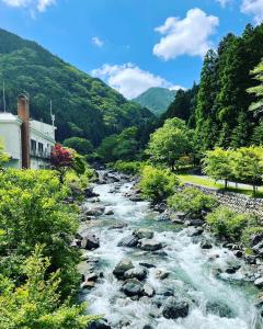 KamikishidaMONJUNO FUKUCHI的一条有岩石、树木和山脉的河流