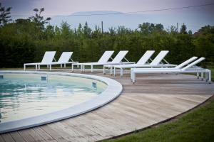 卡多格尼爱卡松尼农场酒店的游泳池旁的一排白色躺椅