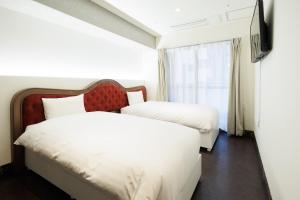 东京Hotaku HOTEL Akihabara的酒店客房设有两张床和电视。