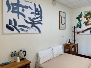 白河People Hostel Taiwan Image Calligraphy Museum的卧室配有一张床,墙上挂有绘画作品