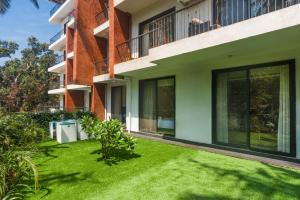 阿伯来Etereo Stays, Luxury Premium Apartments, Arpora, Goa的建筑前的绿色草坪