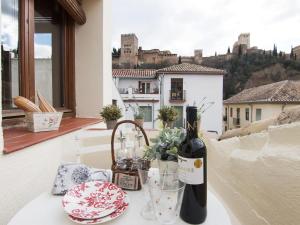 格拉纳达Chezmoihomes Alhambra Penthouse的阳台上的桌子上摆放着一瓶葡萄酒