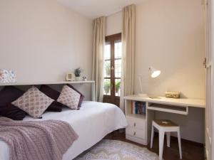 格拉纳达Chezmoihomes Alhambra Penthouse的一间卧室配有一张床、一张书桌和一个窗户。