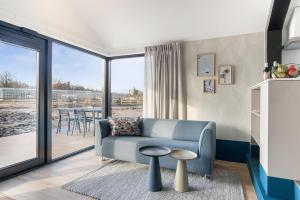 乌得勒支Waterlinie Lodges的一间带蓝色沙发的客厅和一个阳台