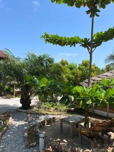 KokrobiteAfrican Treasure Beach Resort的公园里设有长凳、桌子和树木