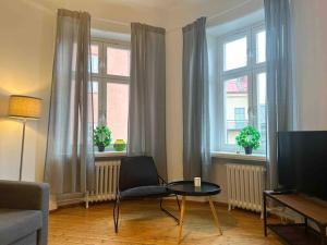 斯德哥尔摩Stay Inn Apartments Norrmalm的一间带椅子和桌子的客厅以及两个窗户。