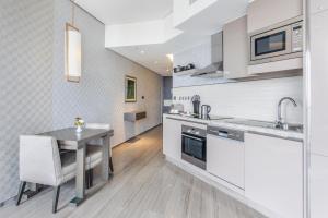 迪拜Spacious Studio Apartment in Hyatt Regency Dubai Creek Heights by the S Holiday Homes的厨房配有白色橱柜和桌椅