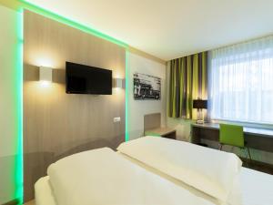 波鸿B&B HOTEL Bochum-Hbf的酒店客房设有一张床、一张书桌和一台电视机。
