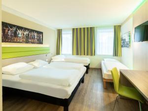 波鸿B&B HOTEL Bochum-Hbf的酒店客房设有三张床和一张桌子