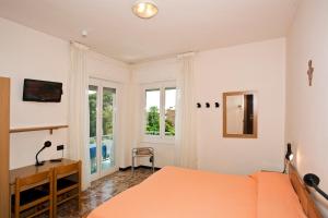阿拉西奥花园酒店的一间卧室配有橙色的床、一张书桌和窗户。