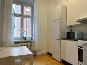 斯德哥尔摩Stay Inn Apartments Norrmalm的白色的厨房配有桌子和微波炉
