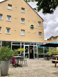 沙特尔B&B HOTEL Chartres Centre Cathédrale的一座大建筑前面设有桌椅