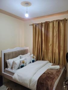内罗毕Gloria House的一间卧室配有带白色床单和枕头的床。
