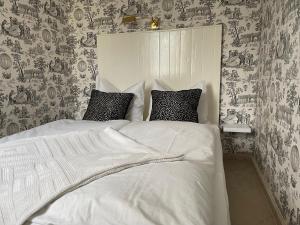 罗斯托克Strandgut的一间卧室配有一张带白色床单和壁纸的床