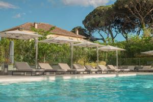 圣特罗佩Kube Saint-Tropez的水边带椅子和遮阳伞的游泳池