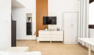 迪拜Manzil - Studio Apartment in Dubai Silicon Oasis near Dubai Outlet Mall的一间配有电视和白色梳妆台的白色客厅