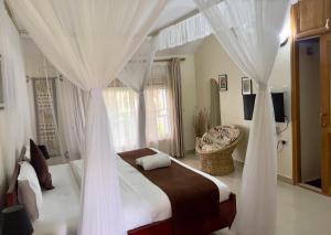 恩德培Sunset Hotel Entebbe的卧室配有带白色窗帘的天蓬床