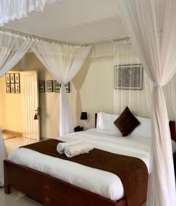 恩德培Sunset Hotel Entebbe的卧室配有一张带白色窗帘的大床