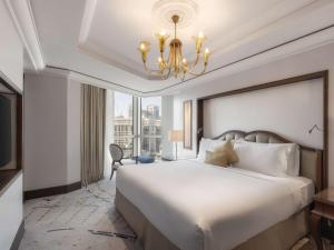 麦加莱佛士酒店的卧室配有一张白色大床和吊灯。