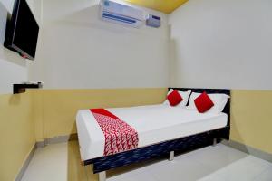 那格浦尔Super OYO Flagship Hotel Vinit Lodging的一间卧室配有一张带红色枕头的床和一台电视。