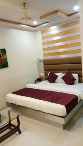 孟买HoteL Namaste London Terminal-2的一间卧室配有一张大床和木制床头板