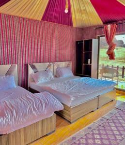 瓦迪拉姆MARS LUXURY CAMP WADi RUM的红色墙壁的客房内的两张床