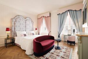 维也纳The Leo Grand的一间卧室配有一张大床和一张红色椅子