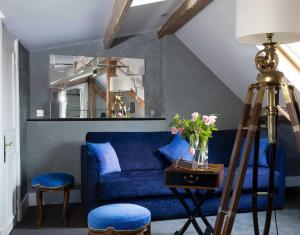 巴黎Hotel & Spa de Latour Maubourg的客厅配有蓝色沙发,设有镜子
