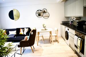 Golders GreenFully Furnished 2 Bed Luxury Apartment with Free Parking,10 mins drive to Wembley Stadium, 5 mins drive to Brent Cross Shopping Mall & Free Parking的厨房以及带桌子和沙发的客厅。