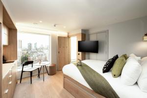 伦敦Wilde Aparthotels London Aldgate Tower Bridge的酒店客房设有一张床和一个大窗户