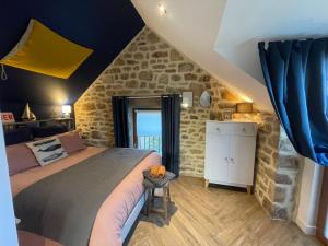 普罗梅尔Gîtes d'Izel n°2的一间卧室设有一张大床和石墙