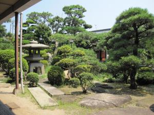 尾道市住之江区旅馆 的一座花园,花园内有塔、树木和灌木