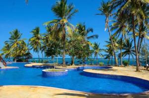 杉祖Lux Suites Lamera Beachfront Apartments的海滩上种有棕榈树的度假游泳池