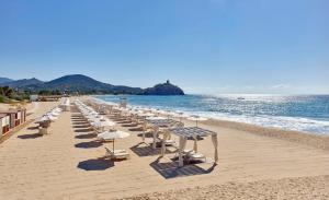 奇亚Baia Di Chia Resort Sardinia, Curio Collection By Hilton的海滩上的一排椅子和遮阳伞